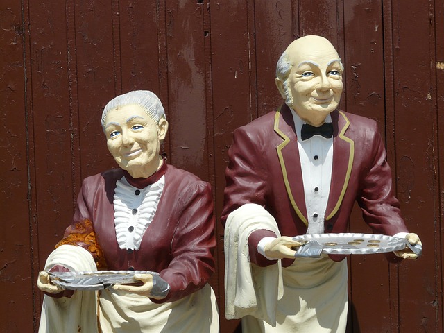 two well dressed servants with sliver serving trays