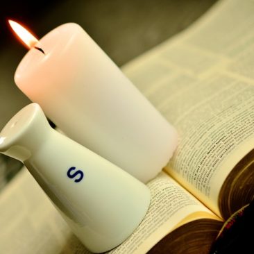 a bible with a salt shaker and and candle resting on it