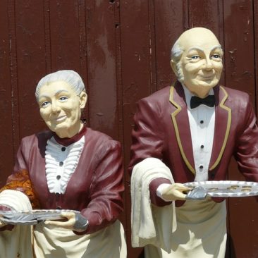 two well dressed servants with sliver serving trays