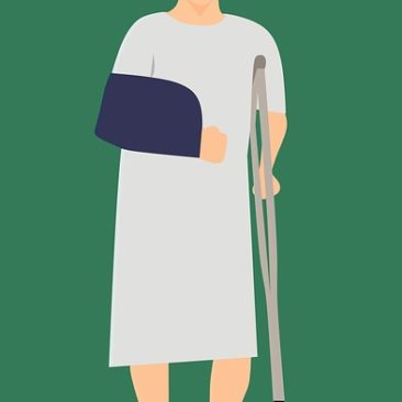 man in hospital gown with a sling and a cane